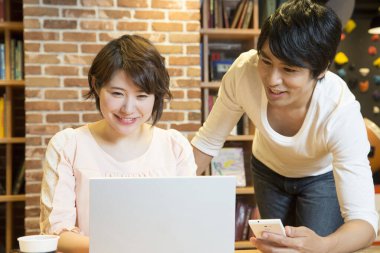 Ofiste bilgisayarla çalışan Asyalı genç kadın ve erkek.