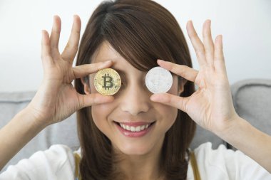 Yüzünün önünde bitcoin tutan bir kadın.