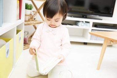 Evde kitabı olan Asyalı küçük kız. 