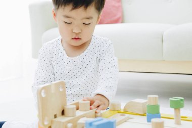 Küçük Asyalı kız ahşap oyuncaklarla oynuyor.