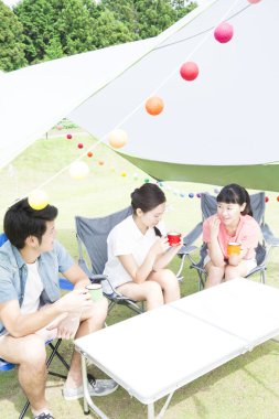 Parkta kamp yapan Asyalı arkadaşlar konuşuyor ve içiyor.