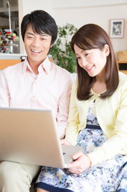 Evde dizüstü bilgisayarda çalışan Asyalı çift. 