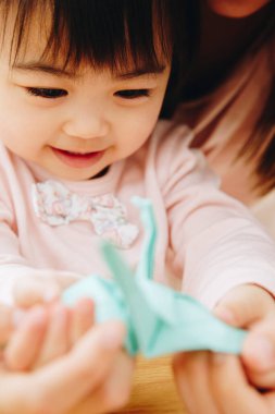 Asyalı anne ve kızı origami yapıyor. 