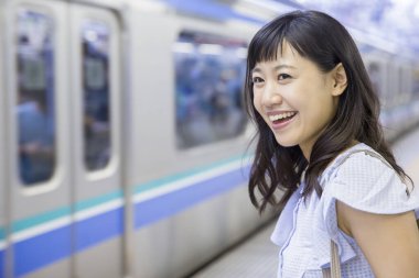 Mutlu Asyalı kadın trene bakıyor.