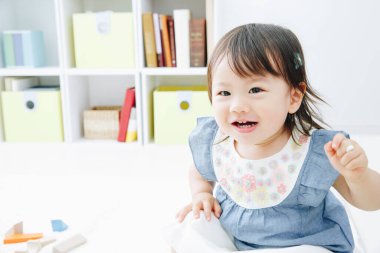 Evdeki oturma odasında oynayan tatlı Asyalı küçük kız.