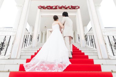 Merdivenlerde kırmızı halıyla yürüyen genç ve güzel bir çiftin arka manzarası. 