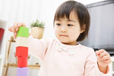 Renkli oyuncaklarla oynayan Asyalı çocuk 