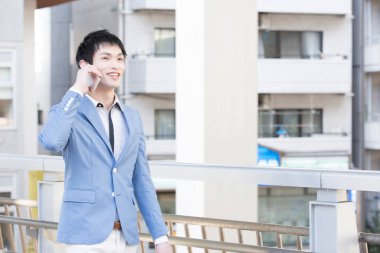 Genç Asyalı iş adamı cep telefonuyla konuşuyor.