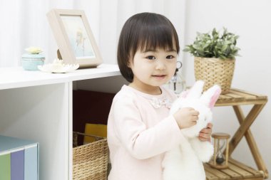 Evinde tavşan oyuncağıyla sevimli küçük bir kız.