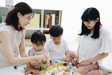 Çocuklarla evde oynayan gülümseyen Asyalı anneler