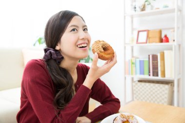 Genç Asyalı kadın donut yiyor. 
