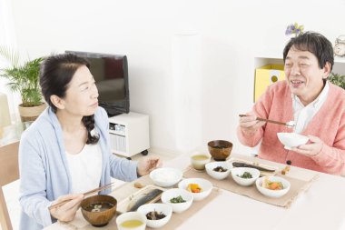 Üst düzey Asyalı çift mutfakta yemek yiyor.