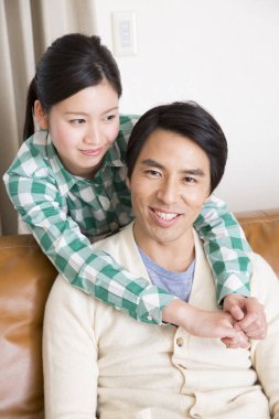 Mutlu Asyalı çift kanepede dinleniyor.