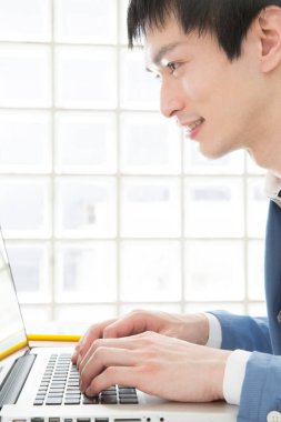 Ofisinde dizüstü bilgisayarda çalışan genç bir adamın portresi.