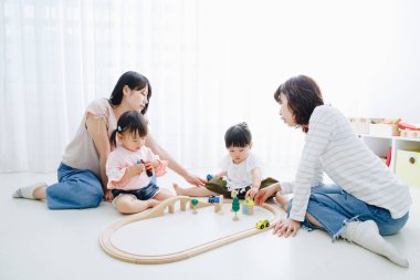 Asyalı anne evde küçük kızlarıyla oynuyor. 