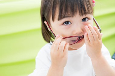 Küçük Asyalı kız gözlükleriyle oynuyor.