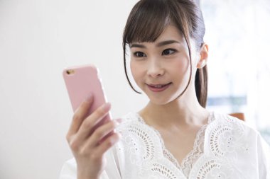 Oturma odasında akıllı telefon kullanan bir kadın.