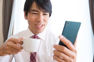 young businessman using a mobile phone and drinking coffee