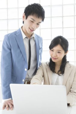 Genç Japon iş adamları ofiste dizüstü bilgisayarla çalışıyorlar.