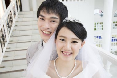 Merdivenlerde poz veren mutlu Asyalı gelin ve damadın portresi.