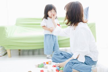 Evdeki oturma odasında annesiyle oynayan tatlı Asyalı küçük kız.