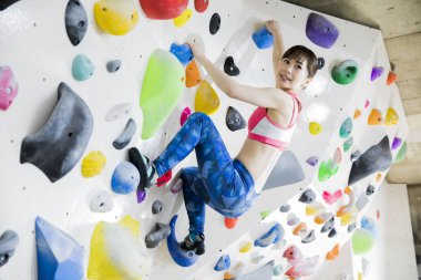 Güzel Japon kadın spor salonunda duvara tırmanıyor. 