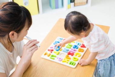 Genç Asyalı kız evde mektup oyuncağıyla oynuyor.