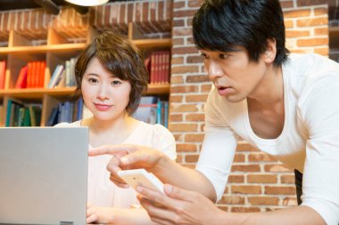 Ofiste bilgisayarla çalışan Asyalı genç kadın ve erkek.