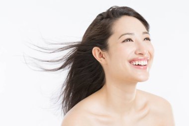 Uçan rüzgâr saçlı mutlu genç kadın beyaz arka planda izole edilmiş.