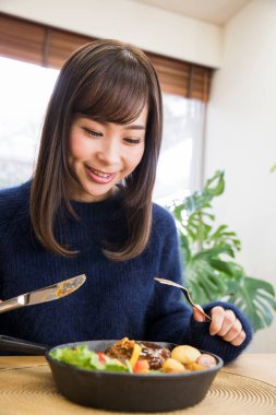 Güzel genç bir kadın Japon restoranında öğle yemeği yiyor.