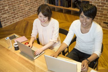 Masada dizüstü bilgisayar kullanan Asyalı çift.