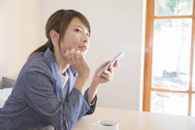 Kafede cep telefonu kullanan Asyalı bir kadın.