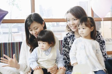 İki küçük çocukla oturan iki kadın.