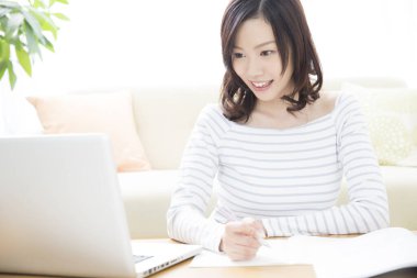 Genç Asyalı öğrenci evde dizüstü bilgisayarla çalışıyor.