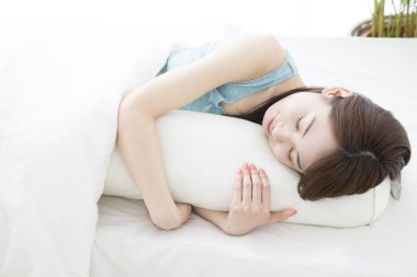 Genç Asyalı kadın beyaz yastıkla uyuyor.