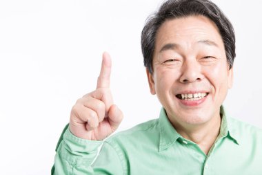 Asyalı kıdemli adam gülümsüyor ve işaret ediyor