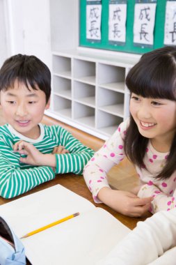 Okul masasında çalışırken gülümseyen çocuklar