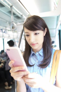 Metroda cep telefonu kullanan Asyalı kadın.