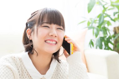 Evde akıllı telefondan konuşan Japon kadının portresi.