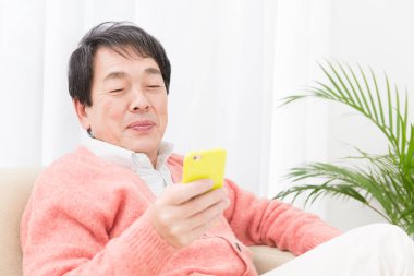 Evde cep telefonu kullanan kıdemli adam.