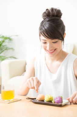 Genç Asyalı kadın kek yiyor. 