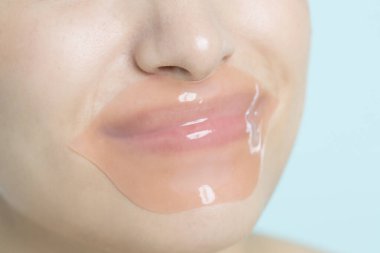Dudaklarında pembe hidrojel bandı olan bir kadının yakın görüntüsü. Kozmetik ve cilt bakımı. Güzellik teni ve kırışıklık önleyici bakım