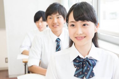 Sınıfta oturan öğrenciler üniforma giyiyor.