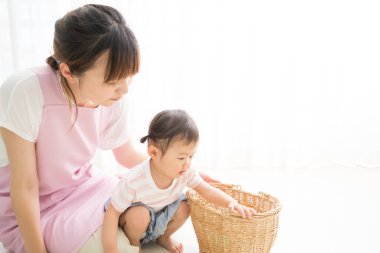 Asyalı anne ve küçük kızı tahta sepetlerle oynuyorlar. 