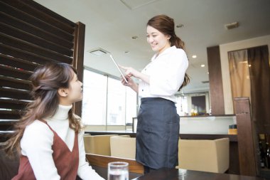 Güzel Japon garson restoranda tabletle sipariş veriyor.