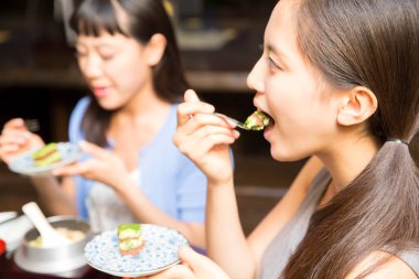 Güzel Asyalı kadınlar restoranda geleneksel Japon yemekleri yiyorlar.