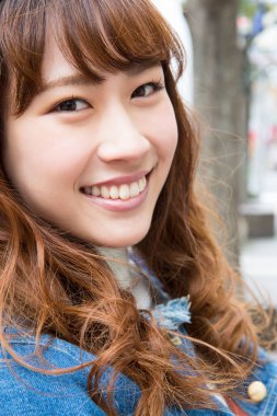 Güzel Asyalı kadın dışarıda kameraya bakıyor.