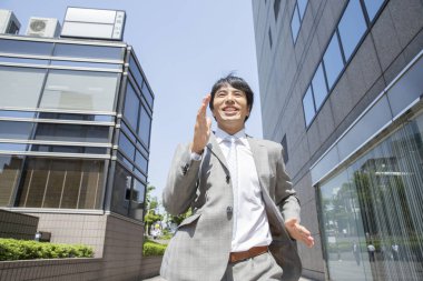 Yakışıklı profesyonel Japon iş adamı sokakta koşuyor.      