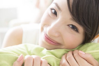 Genç Japon kız yastıkla kanepede yatıyor. 