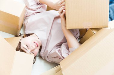 Genç bir kadın karton kutularla yerde yatıyor ve yeni bir daireye taşınıyor..